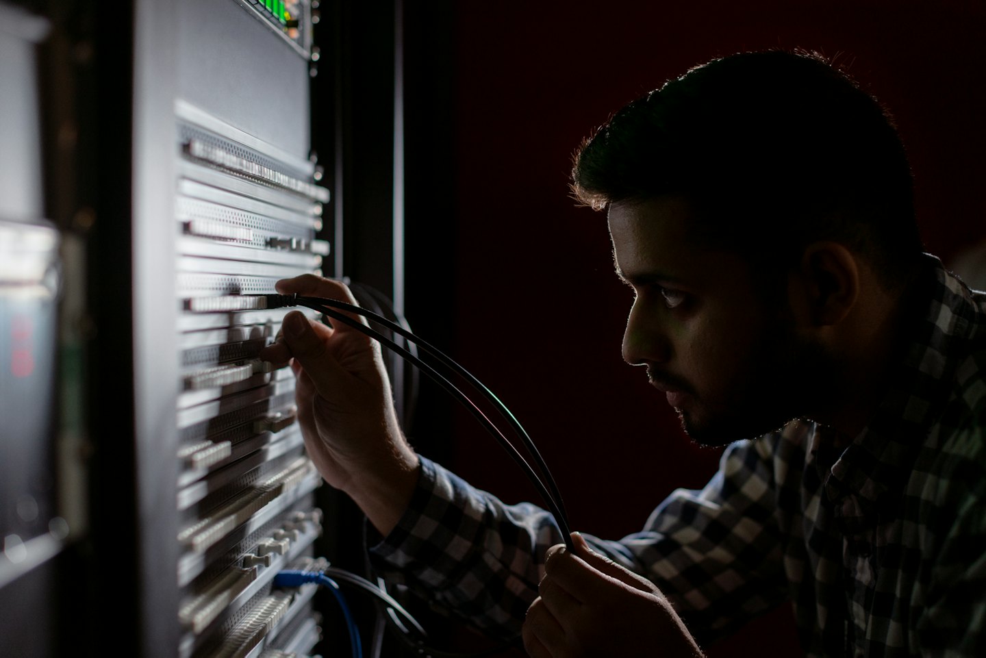 Man connecting cables to a server rack in a data center.
