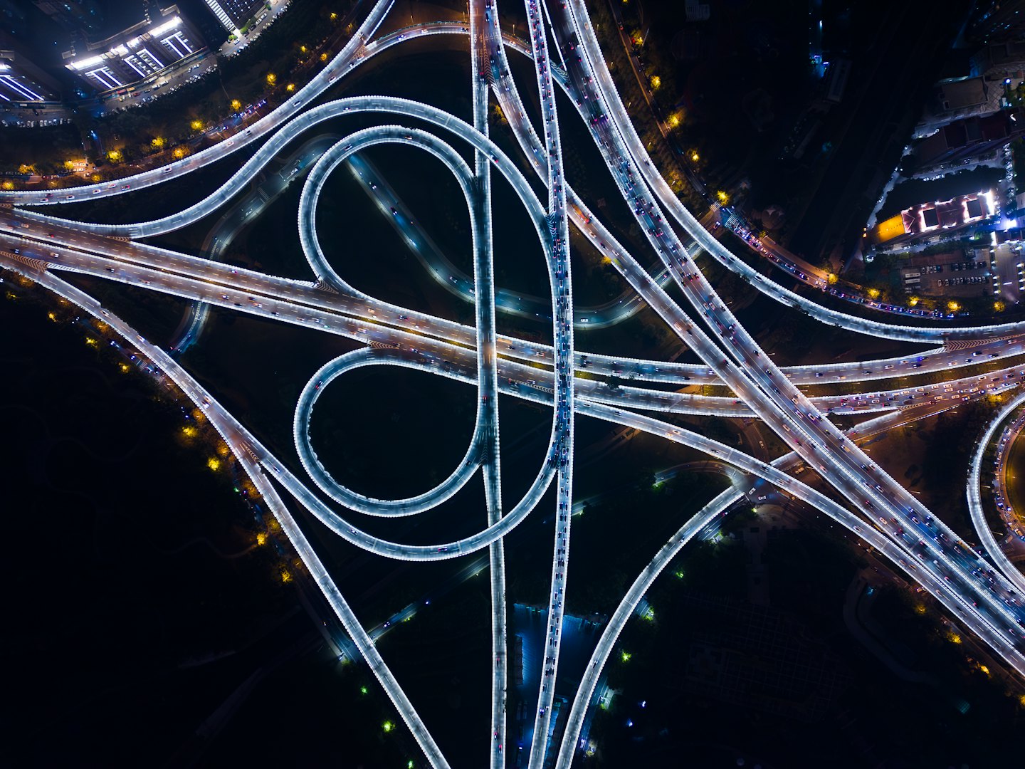 Brightly illuminated highway interchange with cars moving through the night.